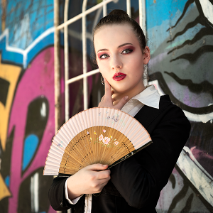 Urban gesture. Leah Bell in a tailored portrait with a fan against a graffiti wall.