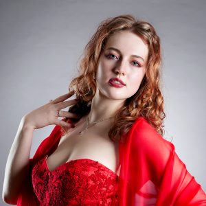 In recital. Leah Bell in a recital portrait wearing a red dress.
