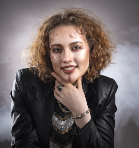 Warmth in gold. Leah Bell in a gold-toned studio portrait, looking ahead with a soft smile.